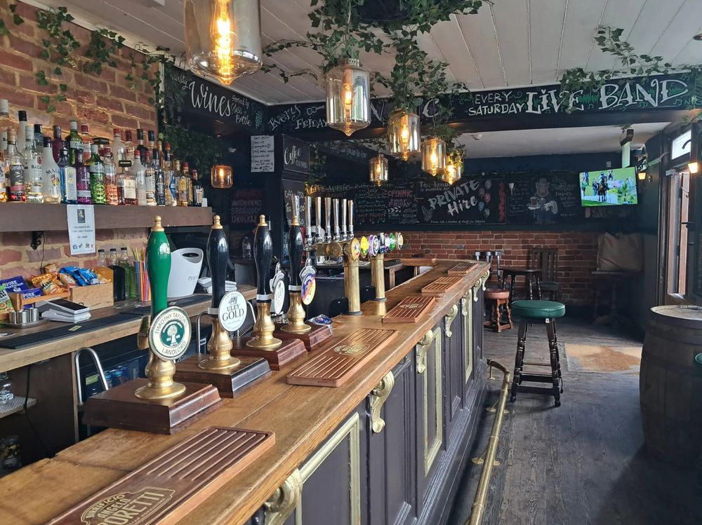 The bar at The Butler, with brass hand pumps and hanging lanterns
